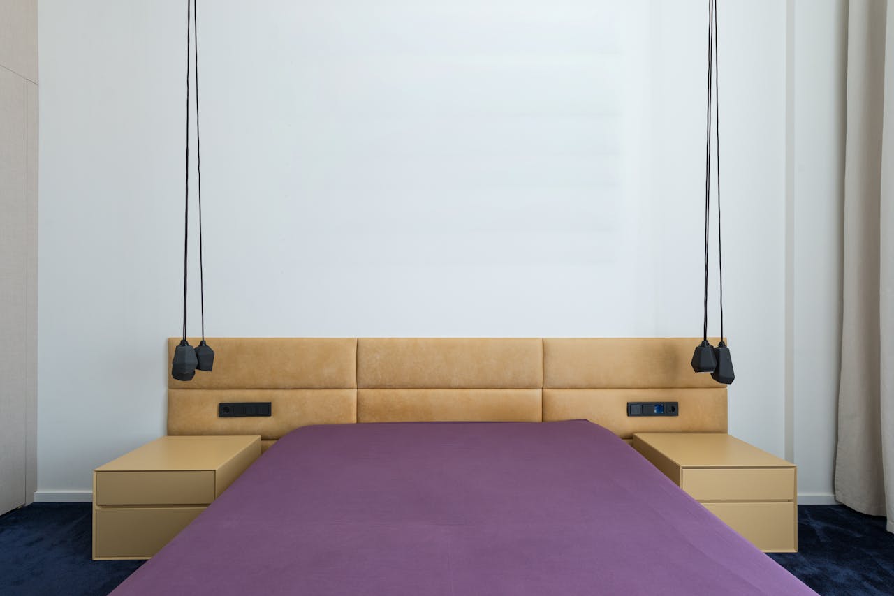 Minimalist interior of contemporary bedroom with bed with headrest and bedsides under stylish lamps